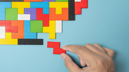 hand connecting geometric shape block with colorful wood puzzle pieces. logical thinking, business logic, Conundrum, decision, solutions, rational, mission, success, goals and strategy concepts