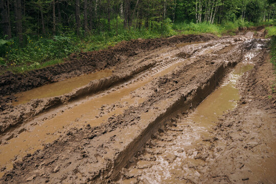 Muddy road with deep vehicle tracks after heavy rain and melting snow, Deep tire tracks in wet, muddy slush, Muddy terrain with tire impressions, challenges of off-road environments 