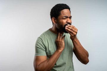 Young african man with sore throat holding neck in pain, uncomfortable expression on face, isolated...
