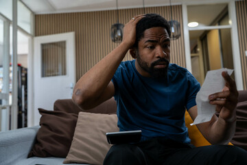 Worried young black man at home feeling stressed about cost of living, rent and food prices,...