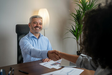 Woman consulting with male financial advisor in modern bank office, discussing contract and...