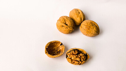 Close-up of whole and cracked walnuts on a white background, showcasing the texture and detail of the nut inside its shell, ideal for healthy food and organic ingredient concepts.