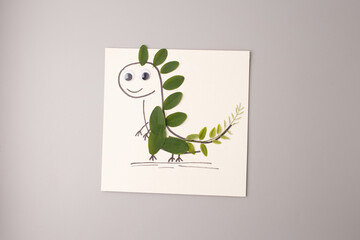 Funny leaf dinosaur made from forest materials by child, great for parenting blogs, educational kits, early childhood programs, environmental campaigns, fall greeting and invitation design