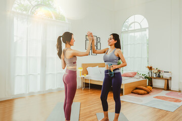 Happiness two young women who are close friends, talking while exercising, standing high fives and drinking water to refresh themselves after completing their activities makes them look cheerful.