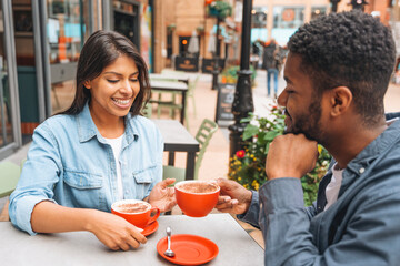 Friends enjoy coffee together at an outdoor café during a sunny day in a bustling urban area, sharing smiles and conversation