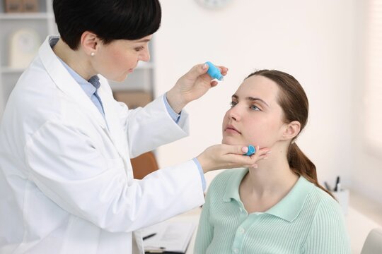 Ophthalmologist applying medical drops onto patient's eye in clinic - Powered by Adobe