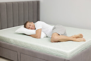 Happy man lying on soft mattress at home