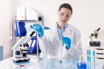 Scientist working with sample in Petri dish at table in laboratory