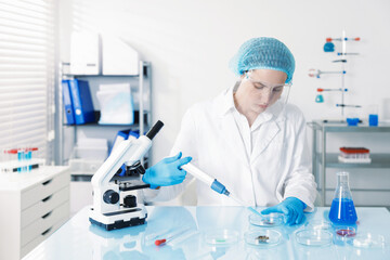 Scientist working with sample in Petri dish at table in laboratory