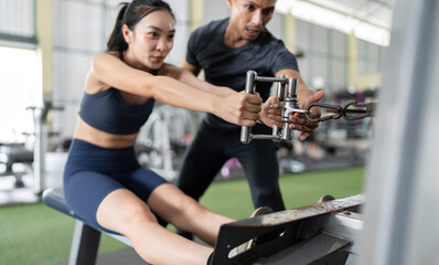 Fitness Trainer Assisting Client with Rowing Machine Workout