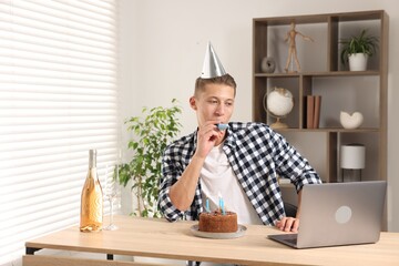 Happy man celebrating his birthday while having video call at desk indoors
