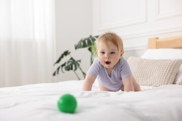 Cute little baby on bed at home, space for text