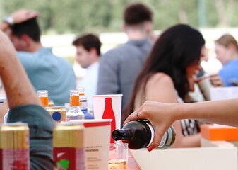 Sirviendo un vaso de vino blanco en la barra de un bar - terraza de verano repleta de gente