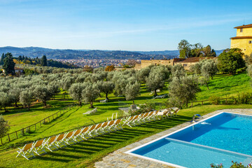 A swimming pool with an olive grove and picturesque Tuscan landscape in Italy.
