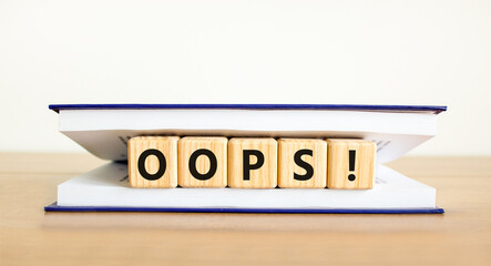Oops symbol. Concept word Oops on beautiful wooden blocks in book. Beautiful wooden table white...