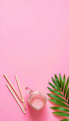 Pink Smoothie in Mason Jar with Straws and Palm Leaf on Pink Background