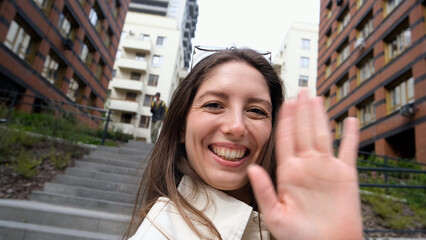 Close-up portrait of attractive young Caucasian girl smiling and looking at camera, taking selfie...