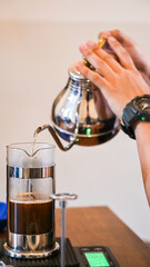 Barista pouring hot water into french press coffee maker