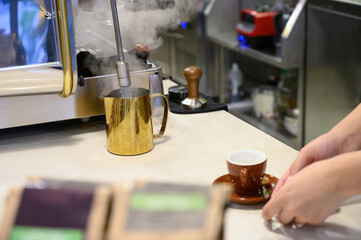 Barista steaming milk for coffee in cafe