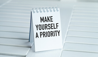 A white notebook with the words Make Yourself a Priority written on it
