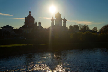 Domes of temples of the Tikhvin Uspensky monastery against the background of the evening autumn sun. Tikhvin, Russia