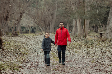 Fototapeta premium papá e hijo caminando juntos de la mano por un camino otoñal