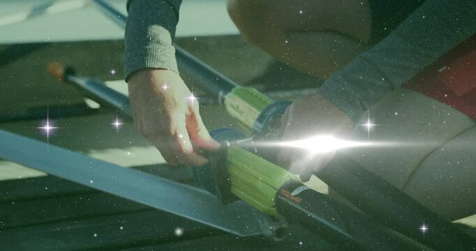 Rower kneeling on dock inserting oar shaft into oarlock securing strap for sports with lens flare