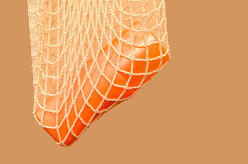 Orange plastic container in white mesh. For cosmetic cream.