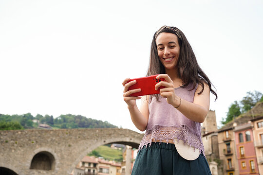 A woman with an ostomy bag in a village looking at her cell phone. Colon Cancer Awareness Day.