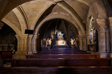 Obraz premium Old stone church interior with wooden benches and religious statues