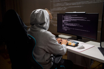 A young programmer codes intently in a dark setting, immersed in his work and creativity