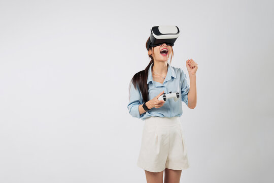 Game becomes real as Excited young Asian woman in VR headset plays console game, fully immersed in futuristic virtual dimension. isolated studio white background - Powered by Adobe