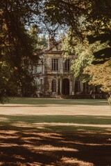 Historic mansion surrounded by trees on a sunny afternoon in a landscaped garden, showcasing classical architecture and serene surroundings ideal for outdoor events or photography