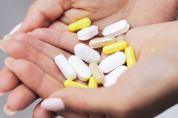Hands holding various pills. Yellow and white capsules. Supplements and vitamins in palm. Pharmaceutical concept. Health care and medication theme. Daily dose of medicine. Nutritional treatment.