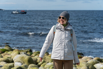 Woman smiles while standing on the distinctive rounded boulders at Dragon Eggs Beach in Teriberka,...