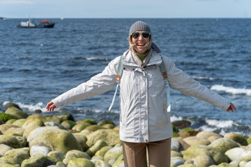 Woman in a white jacket with arms outstretched smiles widely while standing on the round...