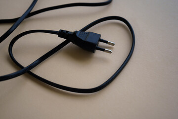 Electric European plug isolated on beige background. Black power cable with plug. Power cord close-up