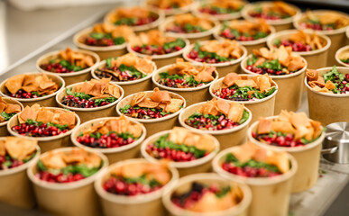 Rows of colorful salads served in eco-friendly paper cups, garnished with pomegranate seeds,...