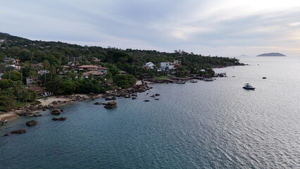 Aerial view of Ilhabela's coastline, featuring palm trees, calm ocean waves, and a tropical beach landscape captured by drone on a bright sunny day along Brazil's southeast coast