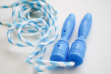 Blue skipping rope isolated on white, top view. Sports equipment
