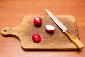 Preparing radishes for a fresh salad on a wooden cutting board with a sharp knife in a cozy kitchen...