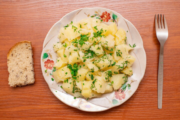 Freshly prepared boiled potatoes served with herbs and bread on a rustic wooden table