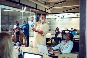 Diverse business team wearing masks during office presentation meeting