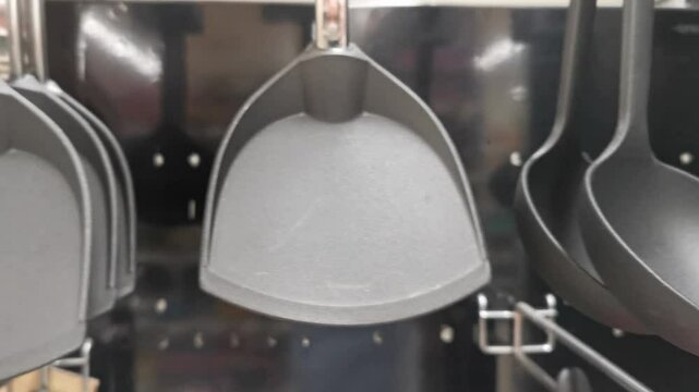 Row of black spoons hanging on a wall. The spoons are all the same size and shape