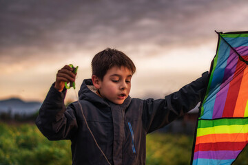 niño jugando a elevar una cometa de múltiples colores en un día nublado