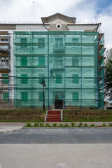 An old building in scaffolding during renovation and painting of the facade.
