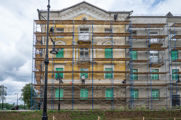 An old building in scaffolding during renovation and painting of the facade.
