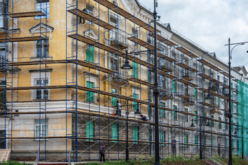 An old building in scaffolding during renovation and painting of the facade.