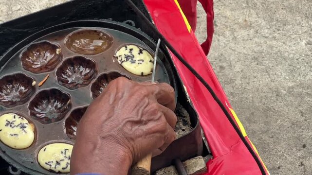 Street vendor preparing kue cubit &mdash; a popular Indonesian mini pancake snack cooked fresh on the roadside, loved for its soft texture and nostalgic flavor. Karet, Indonesia - June 25, 2025