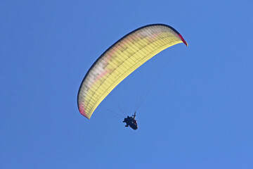 Tandem Paraglider flying in a blue sky	